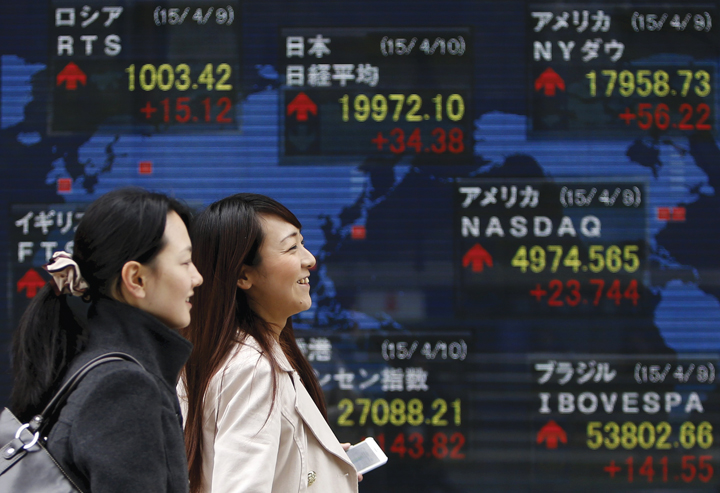 Pedestrians walk past an electronic board showing the stock market indices of various countries outside a brokerage in Tokyo in this file photo taken on April 10, 2015. REUTERS/Yuya Shino